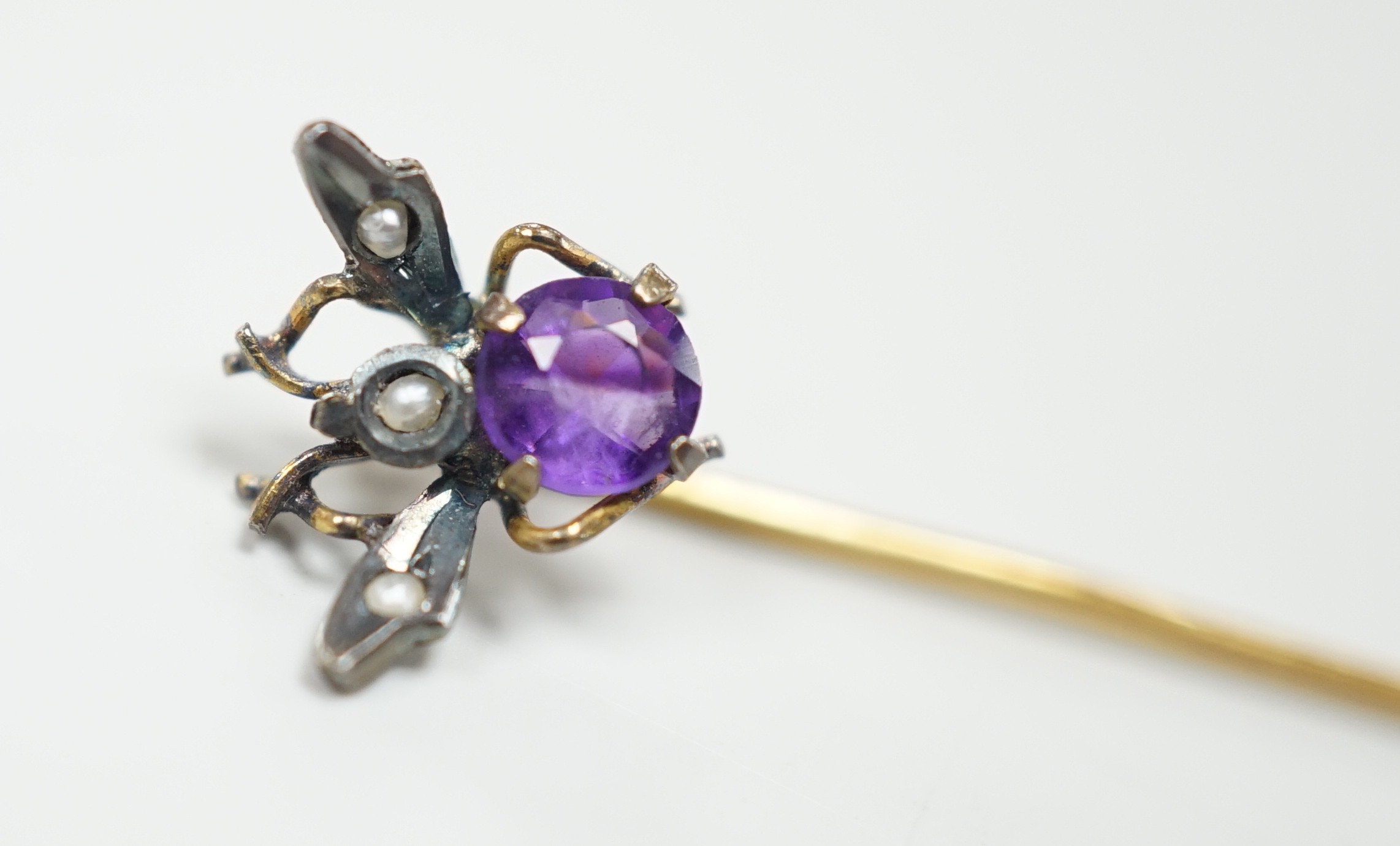 An early 20th century yellow and white metal amethyst and seed pearl set bug stick pin, 4mm, gross weight 0.6 grams.